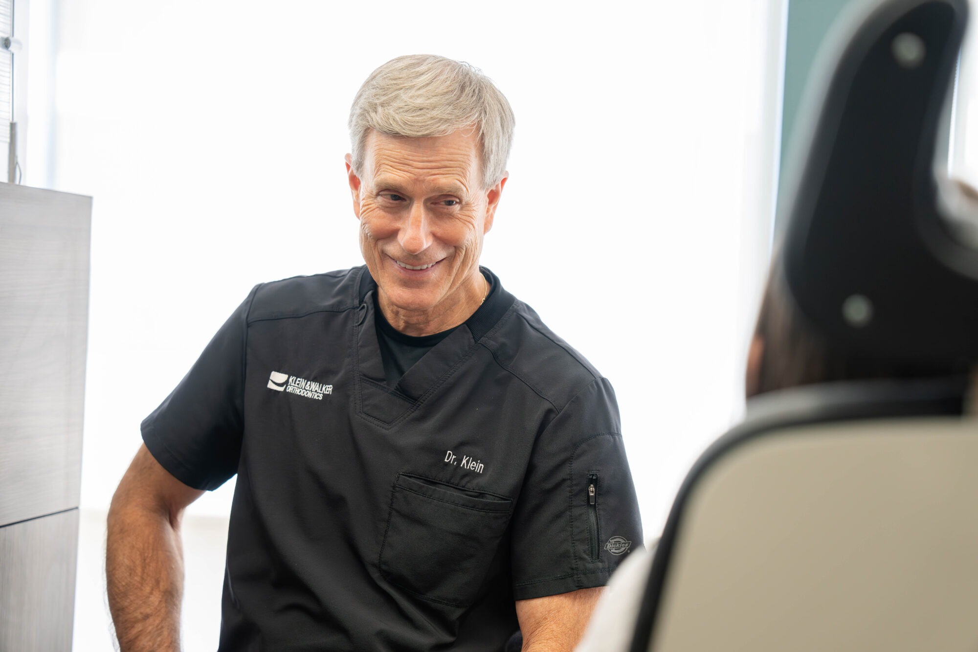 Orthodontist Dr. Klein smiling and engaging with a patient in a modern orthodontic office at Klein Walker & Weber Orthodontics, West Olathe.