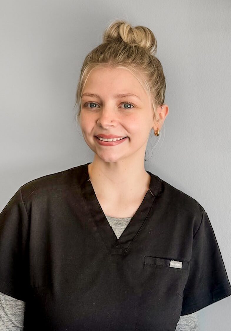 Ellen - Ortho Assistant. Ellen, orthodontic assistant at Klein Walker & Weber Orthodontics, smiling in a black uniform against a gray background.