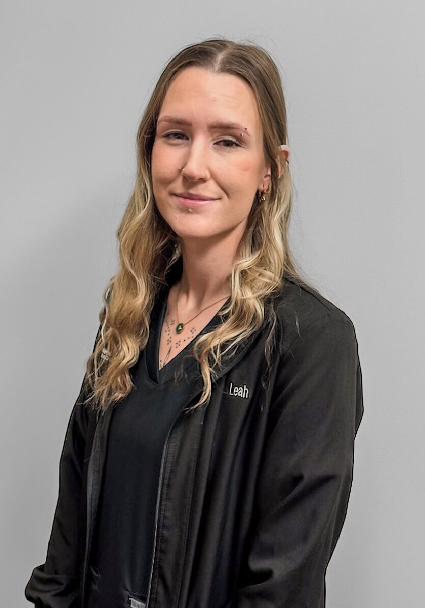 Leah - Ortho Assistant Leah, orthodontic assistant at Klein Walker & Weber Orthodontics, smiling in a black jacket against a gray background.
